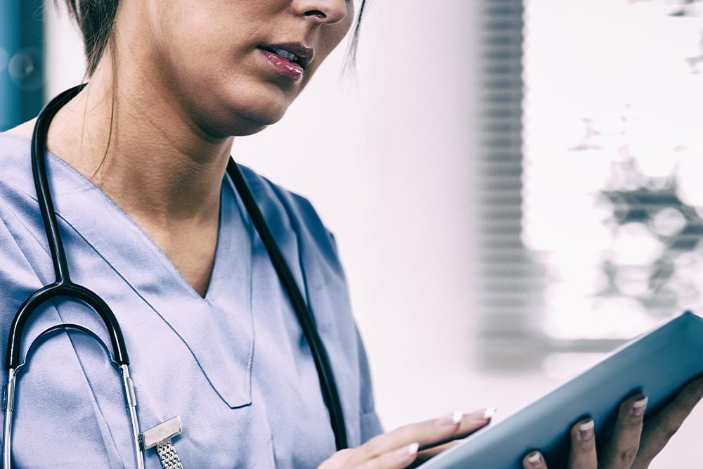 doctor-in-scrubs-flips-through-mobile-tablet