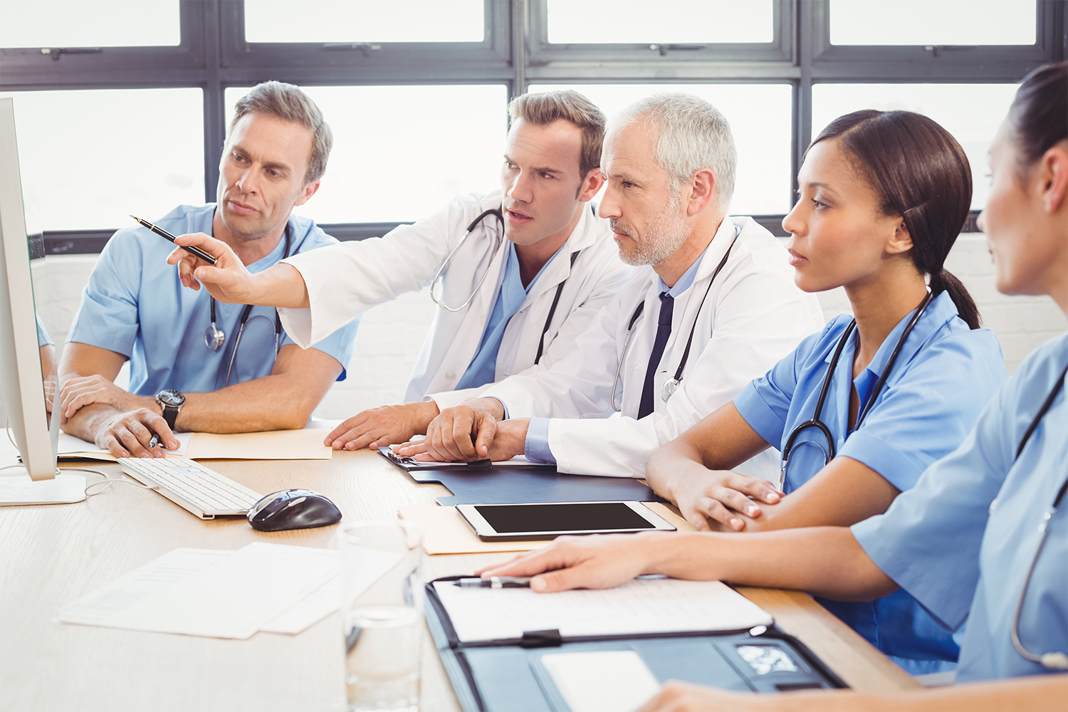 doctors at a conference table viewing a computer monitor