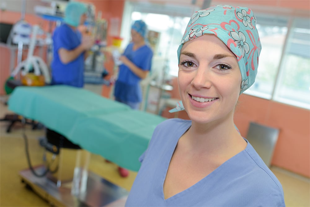 Female healthcare worker in scrubs standing in an operating room